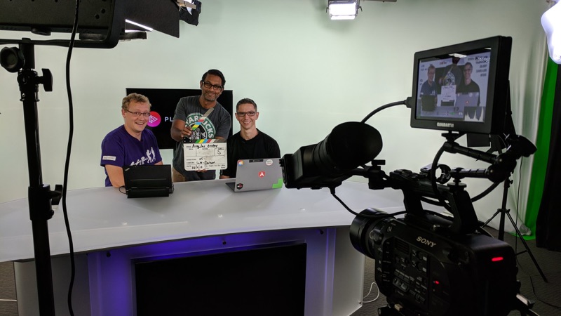 Three people at a desk in the Pluralsight studio, a clapperboard reading Angular Testing, a camera in the foreground.
